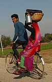 Inderin mit Kopflast auf dem Fahrrad - Streetlife in Indien